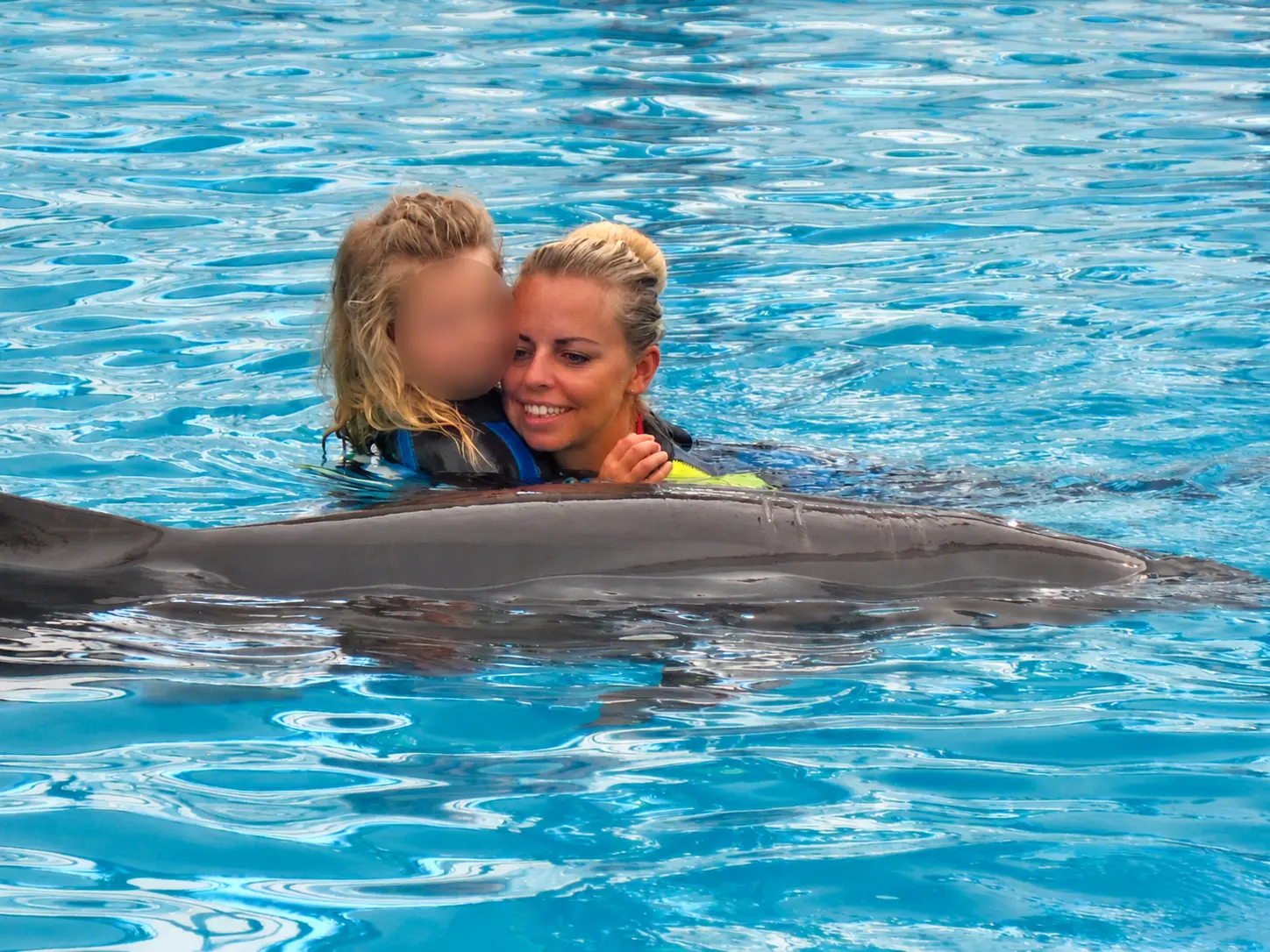 Kinder schwimmen gemeinsam mit einem Delfin im Wasser