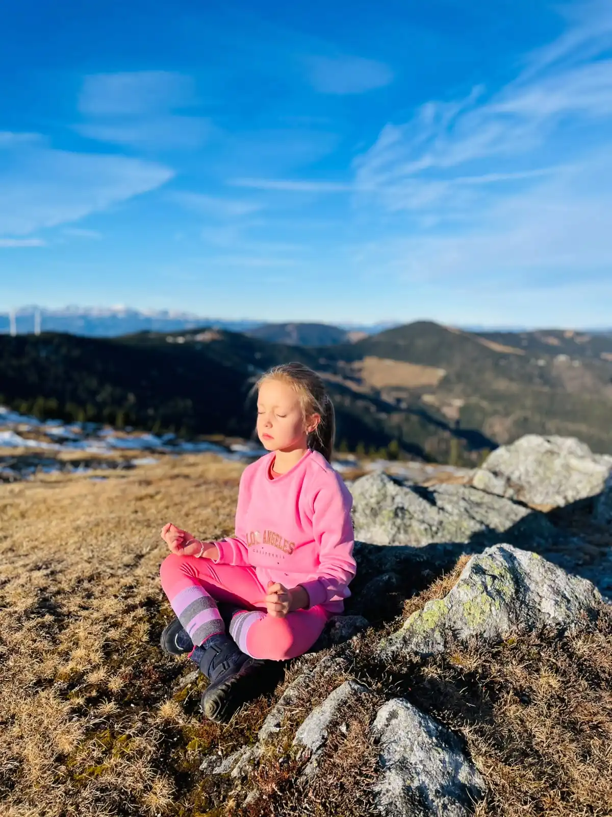 Mädchen in Meditation mit Bergpanorama im Hintergrund