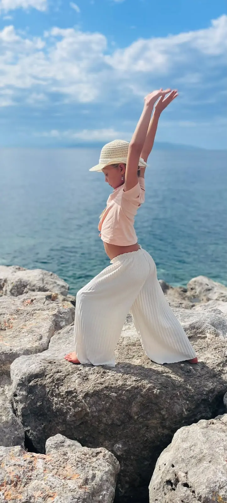 Mädchen beim Kinder-Yoga auf einem Felsen am Meer